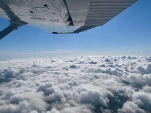 wing view of flying over clouds, looking outside of cessna 172 aircraft