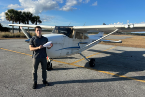 Student standing in front of Cessna 172 with pilot certificate