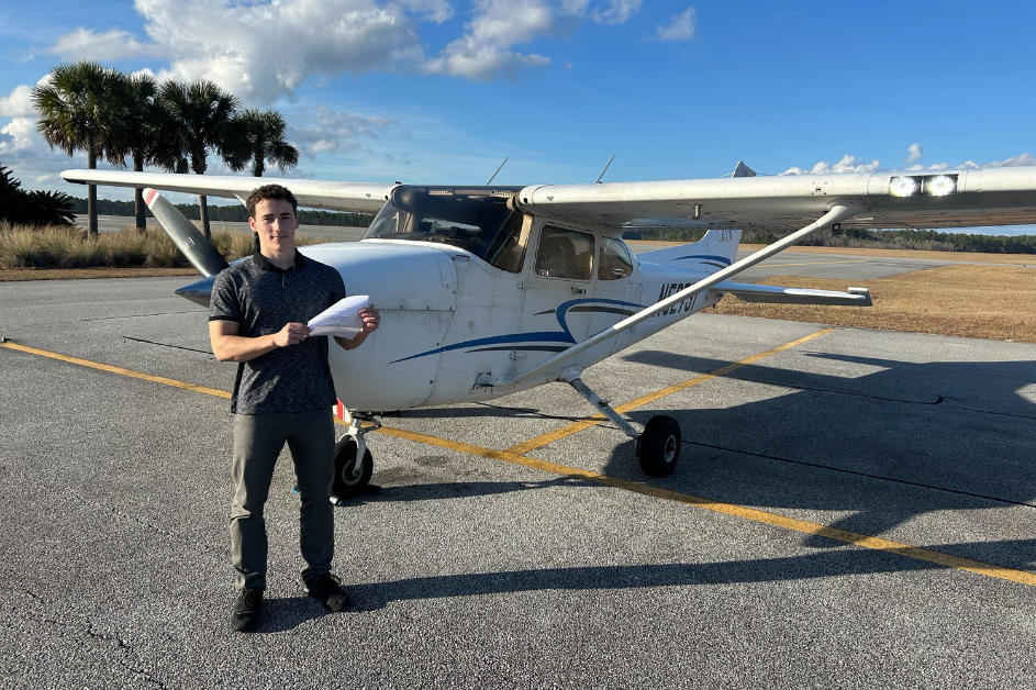 Student standing in front of Cessna 172 with pilot certificate